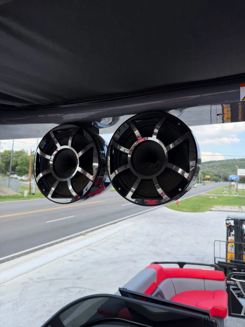 Slide: The Image of Two large speakers are mounted under a boat canopy, with a road in the background. - 16