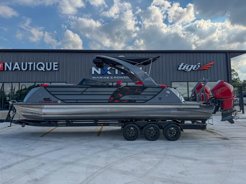 The Image of A modern Trifecta 25 SPORT RF9 DC 3.0 ARCH boat on a trailer in front of a building. - 1