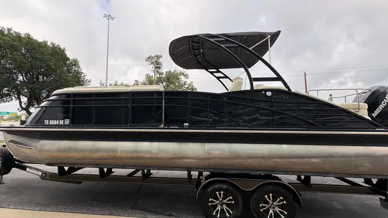 Slide: The Image of A 2015 Bennington 2575 QCW pontoon boat on a trailer, featuring a black canopy and Mercury engine. - 4