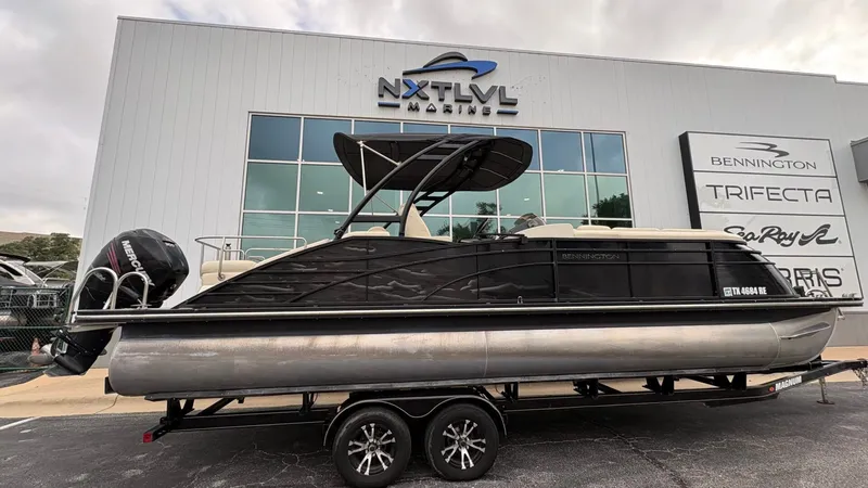 Slide: The Image of A 2015 Bennington 2575 QCW pontoon boat on a trailer in front of a modern building. - 3