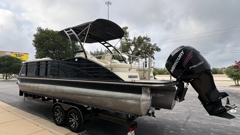Slide: The Image of A 2015 Bennington 2575 QCW pontoon boat with a Mercury outboard motor, parked on a trailer. - 5