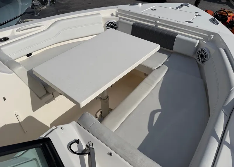 Slide: The Image of The image shows the bow area of a Cobia 240 Dual Console boat with a table and seating. - 7