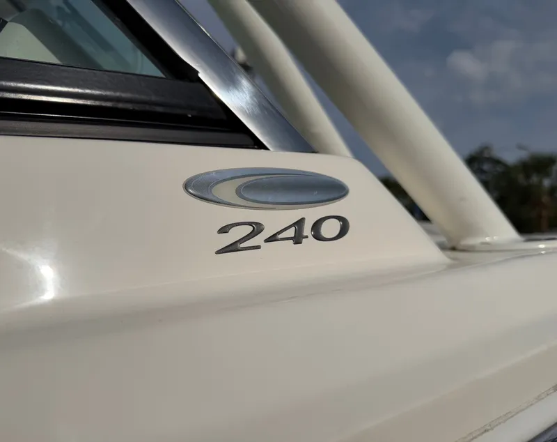 Slide: The Image of Close-up of the Cobia 240 Dual Console logo on a cream-colored boat. - 32