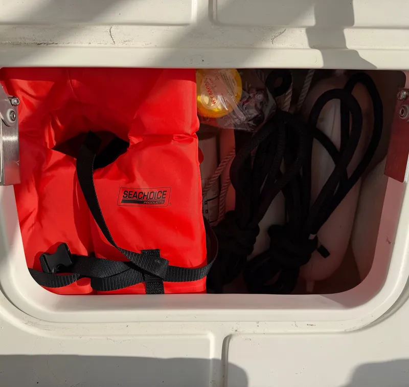 Slide: The Image of An open storage compartment with an orange life jacket, ropes, and a small canister. - 26