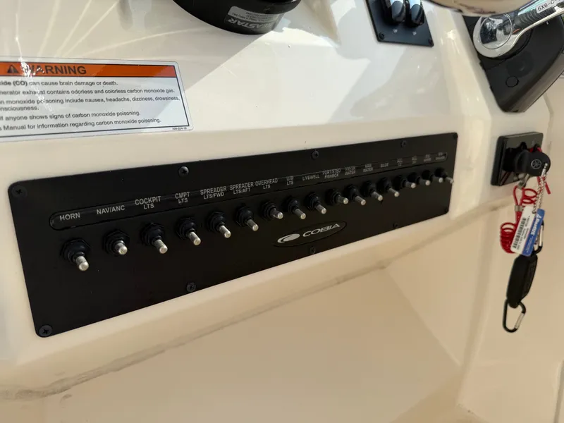 Slide: The Image of Control panel of a 2021 Cobia 240 Dual Console boat with various switches and warning labels. - 17