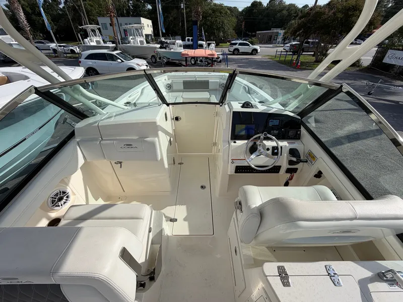 Slide: The Image of The image shows the cockpit of a 2021 Cobia 240 Dual Console boat with white seating and helm. - 10