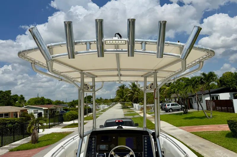 Slide: The Image of 2020 Robalo R230 Center Console boat with T-top and rod holders on a sunny street. - 38