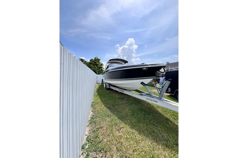 Slide: The Image of 2015 Formula 330 Crossover Bowrider on trailer, parked beside a white fence under blue sky. - 28