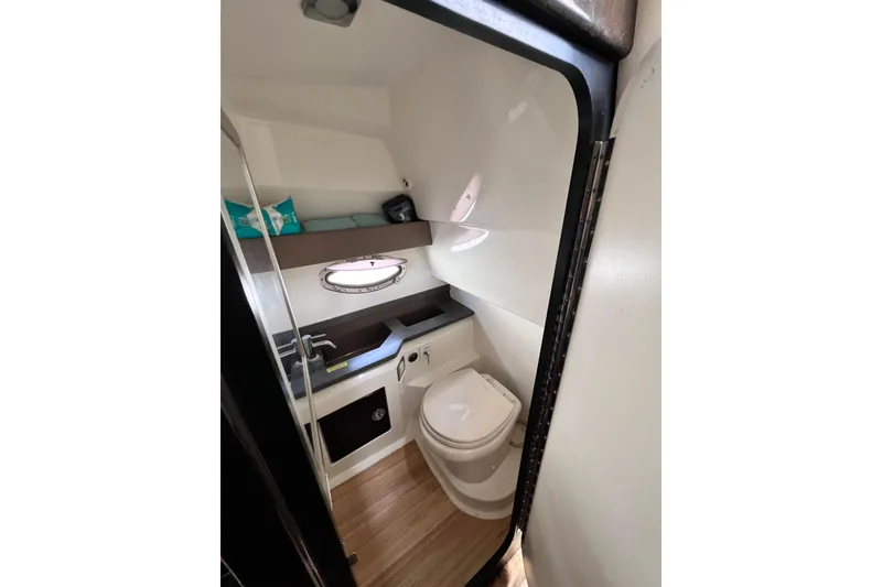Slide: The Image of 2015 Formula 330 Crossover Bowrider bathroom with toilet, sink, and porthole window. - 21