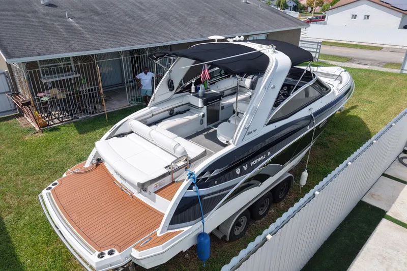 Slide: The Image of 2015 Formula 330 Crossover Bowrider boat parked on trailer in residential yard. - 1