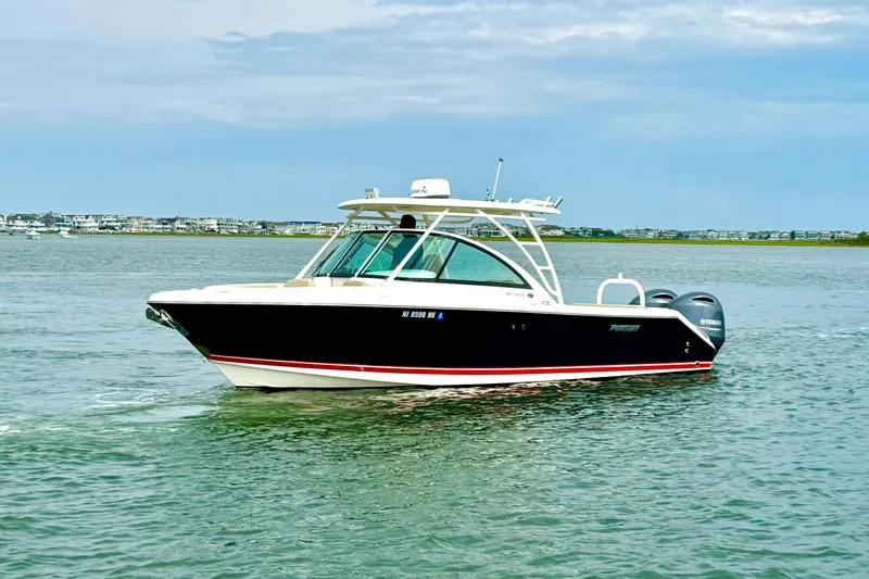 Slide: The Image of 2016 Pursuit DC 265 Dual Console boat cruising on calm waters under a cloudy sky. - 4