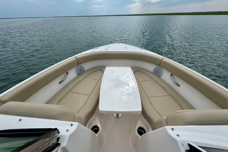 Slide: The Image of 2016 Pursuit DC 265 Dual Console boat interior with beige seating on calm water. - 9