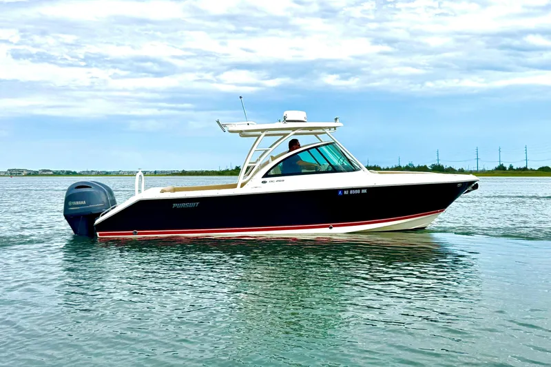 Slide: The Image of 2016 Pursuit DC 265 Dual Console boat on calm water with Yamaha outboard motor. - 2