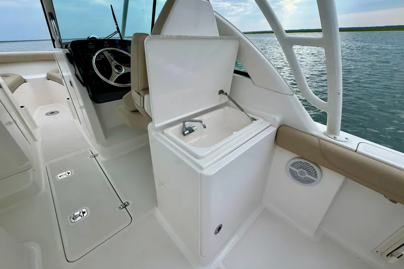Slide: The Image of 2016 Pursuit DC 265 Dual Console boat interior with helm, sink, and seating. - 13