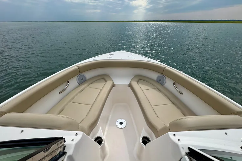 Slide: The Image of 2016 Pursuit DC 265 Dual Console boat interior with beige seating, overlooking calm waters. - 10