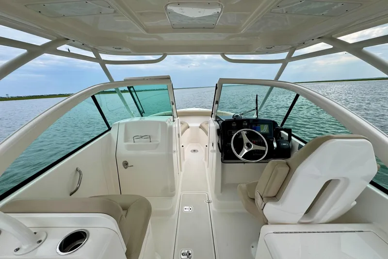 Slide: The Image of 2016 Pursuit DC 265 Dual Console boat interior with steering wheel and seating on open water. - 6