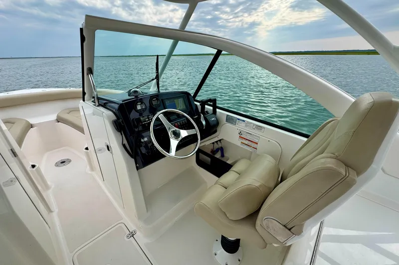 Slide: The Image of 2016 Pursuit DC 265 Dual Console boat interior with steering wheel and comfortable seating. - 7