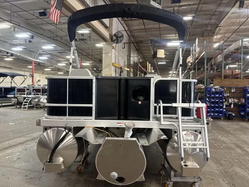 The Image of A Bennington 22 S1 Fish and Cruise pontoon boat in a warehouse. It features a black canopy and ladder. - 1
