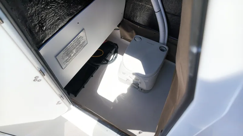 Slide: The Image of The image shows a small toilet inside a boat, surrounded by white and black surfaces. - 20