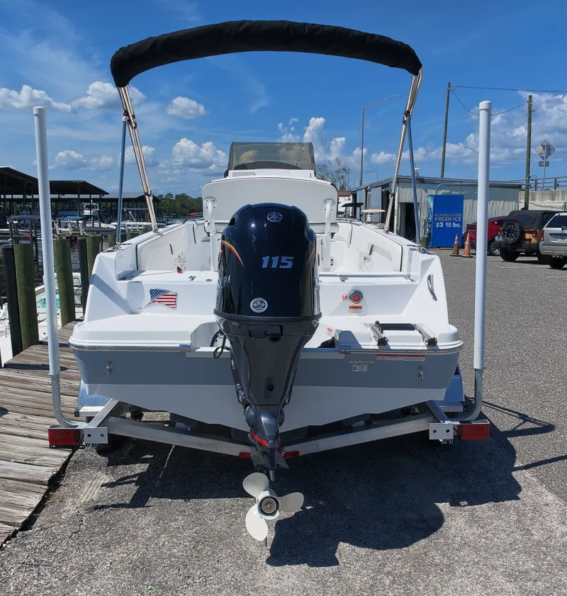 Slide: The Image of A white boat with a 115 HP outboard motor sits on a trailer at a dock. - 3