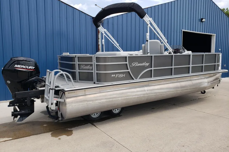 The Image of 2023 Bentley Pontoons 223 4 Party Fish boat with Mercury engine, parked by a blue building. - 1