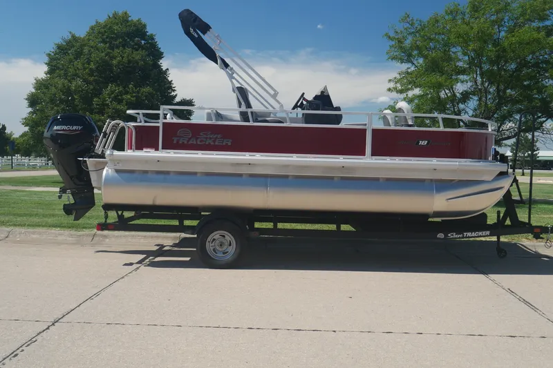 The Image of 2026 Sun Tracker Bass Buggy 18 DLX pontoon boat on trailer, parked outdoors. - 0
