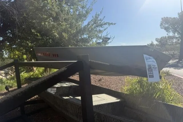 Slide: The Image of 2026 Tracker Grizzly 10 Jon boat displayed outdoors on a wooden rack. - 2