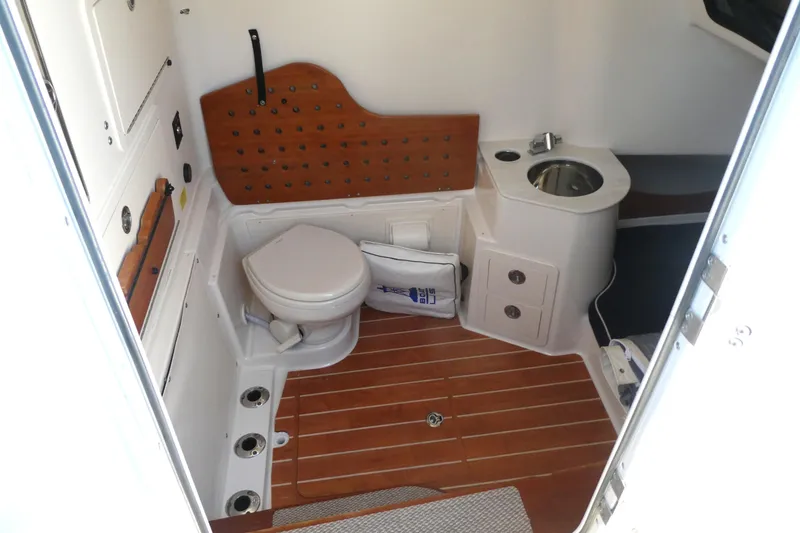 Slide: The Image of 2019 Grady-White Canyon 336 boat interior with toilet and sink, featuring wooden flooring. - 9
