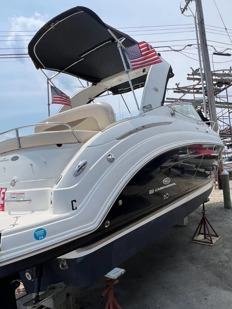 Slide: The Image of 2006 Chaparral Signature 276 boat with canopy and American flags, docked on land. - 4