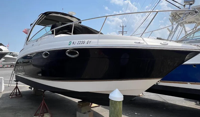 Slide: The Image of 2006 Chaparral Signature 276 boat on stands, black and white exterior, docked outdoors. - 2