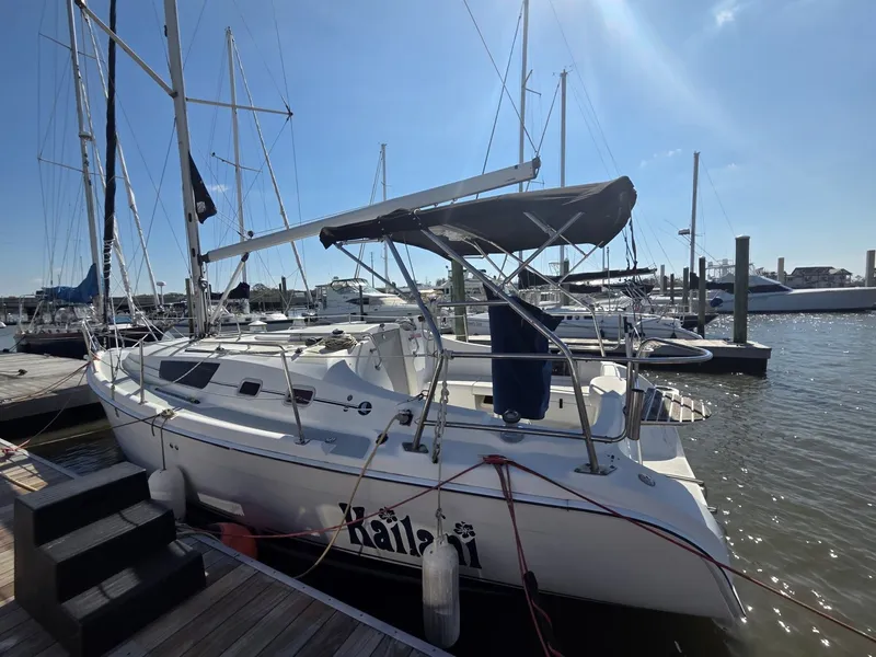 Slide: The Image of A 2005 Hunter 31 sailboat docked on a sunny day, with other boats in the background. - 2