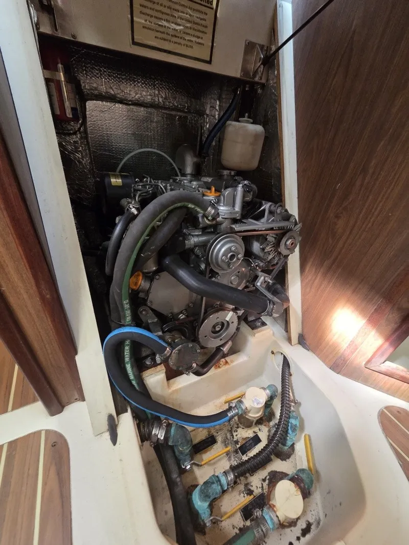 Slide: The Image of The engine compartment of a 2005 Hunter 31 shows a well-maintained engine with hoses and valves. - 10