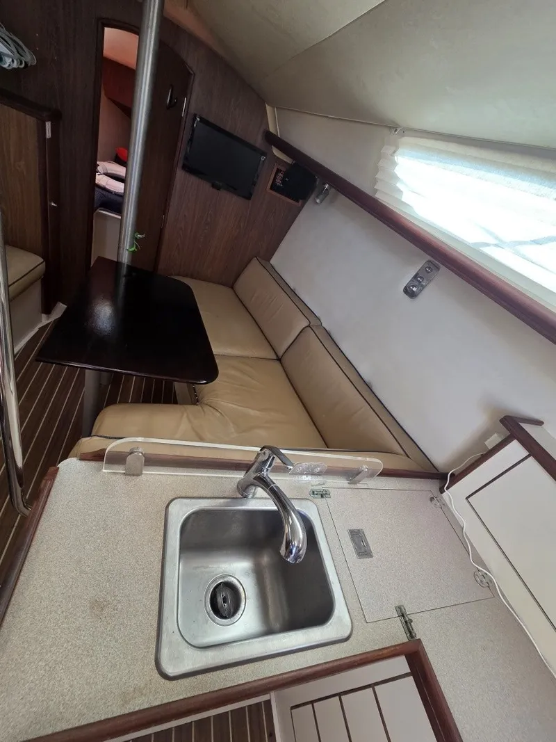 Slide: The Image of Interior view of a 2005 Hunter 31 featuring a small kitchen and seating area. - 5