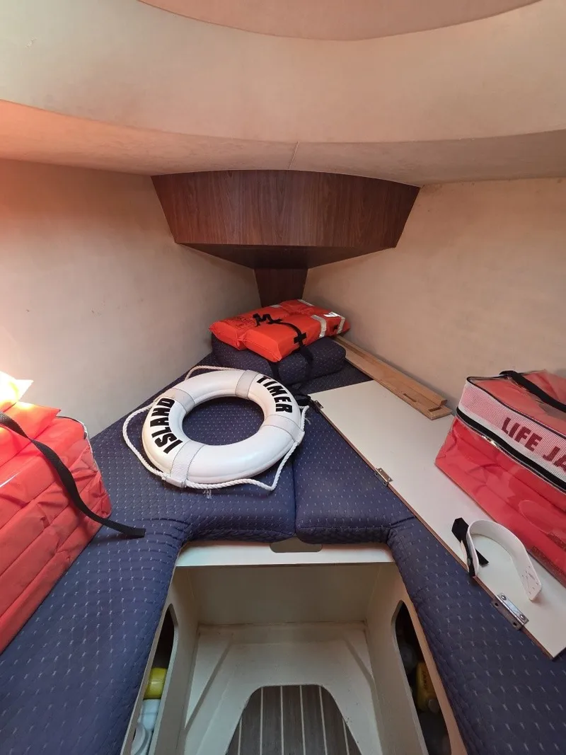 Slide: The Image of The cabin of a 2005 Hunter 31 features blue cushions, life jackets, and a life ring. - 7