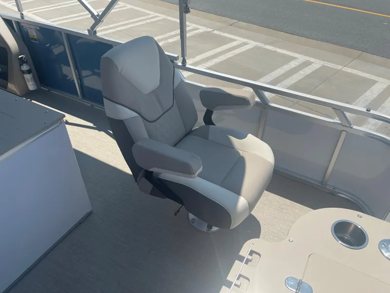 Slide: The Image of A comfortable captain's chair on a 2024 Avalon LSZ Rear Fish boat, featuring armrests and a table with cup holders. - 23