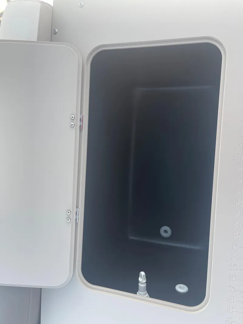 Slide: The Image of An open storage compartment on a 2024 Avalon LSZ Rear Fish boat. - 27