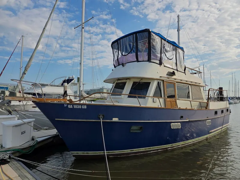 The Image of A blue and white 1982 Sea Ranger 39 Sundeck docked in a marina, surrounded by other boats. - 0