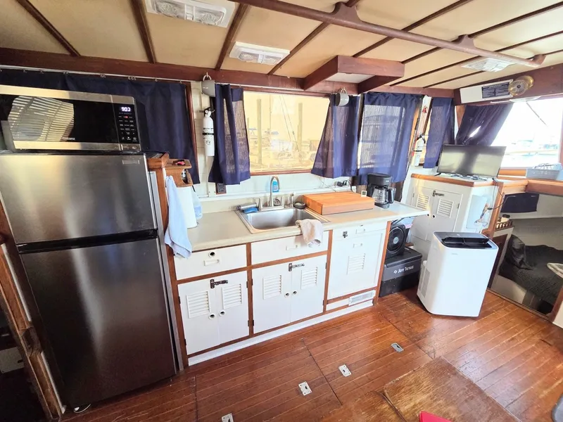 Slide: The Image of Interior of a 1982 Sea Ranger 39 Sundeck with kitchen, refrigerator, and wooden floor. - 3