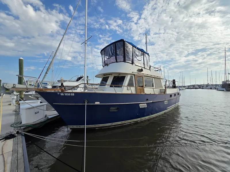 Slide: The Image of A 1982 Sea Ranger 39 Sundeck docked at a marina. The sky is partly cloudy. - 15