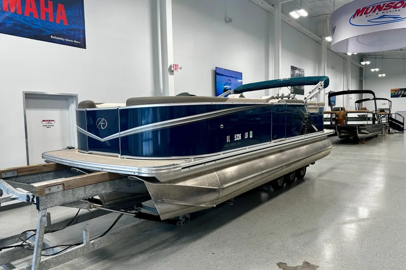 Slide: The Image of 2022 Avalon LSZ 2285 CR pontoon boat displayed indoors on a trailer. - 12