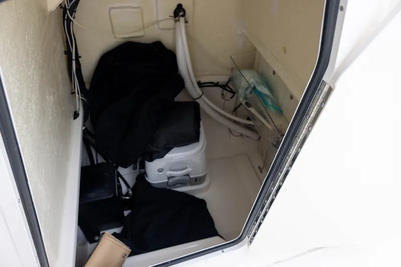 Slide: The Image of The interior of a 2022 Bayliner T22CX shows a small storage area with a portable toilet. - 10