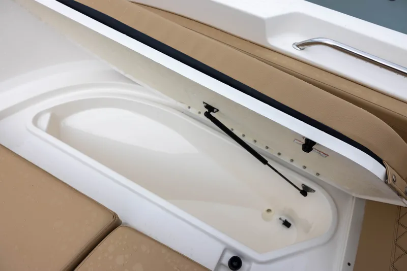 Slide: The Image of An open storage compartment on a 2022 Bayliner T22CX boat with beige upholstery. - 15