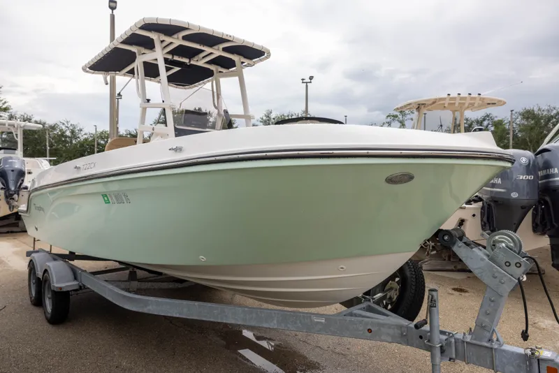 Slide: The Image of A 2022 Bayliner T22CX on a trailer, featuring a white hull and a T-top. - 2
