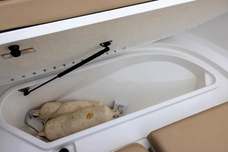 Slide: The Image of An open storage compartment on a Bayliner T22CX boat with two fenders inside. - 14