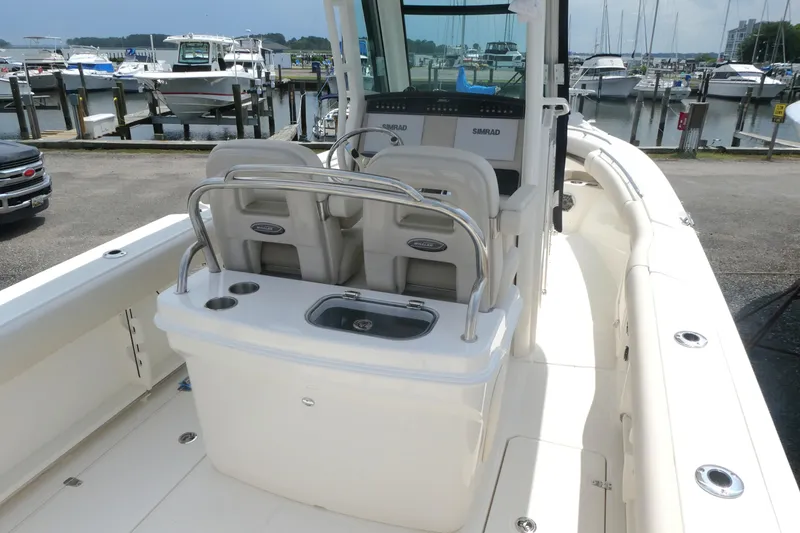 Slide: The Image of 2027 Boston Whaler 250 Outrage boat interior at marina, featuring helm and seating area. - 5