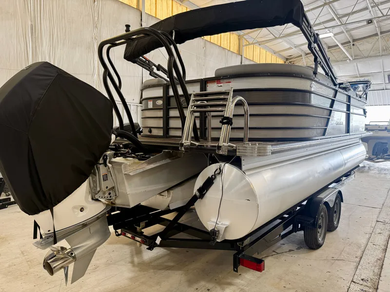 Slide: The Image of A 2022 Crest Classic Platinum 220 SLC pontoon boat in a warehouse. It features an outboard motor and black canopy. - 15