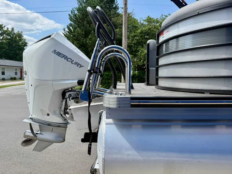 Slide: The Image of A Mercury outboard motor is attached to a pontoon boat. The background shows trees and a house. - 20
