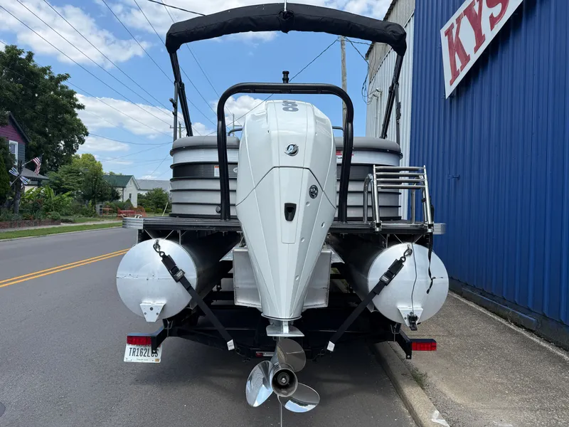 Slide: The Image of A 2022 Crest Classic Platinum 220 SLC pontoon boat with a large outboard motor, parked on a street. - 12
