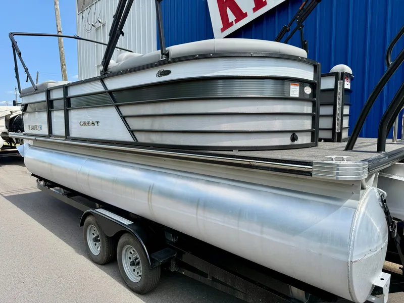 Slide: The Image of 2022 Crest Classic Platinum 220 SLC pontoon boat on a trailer, featuring a silver hull and black railing. - 18
