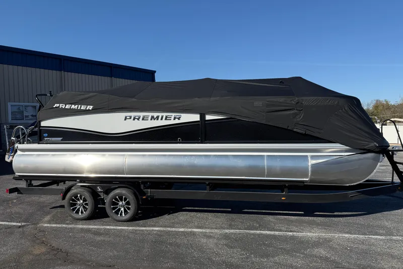 Slide: The Image of 2026 Premier 230 SunSation RF pontoon boat with cover on trailer, parked outdoors. - 38